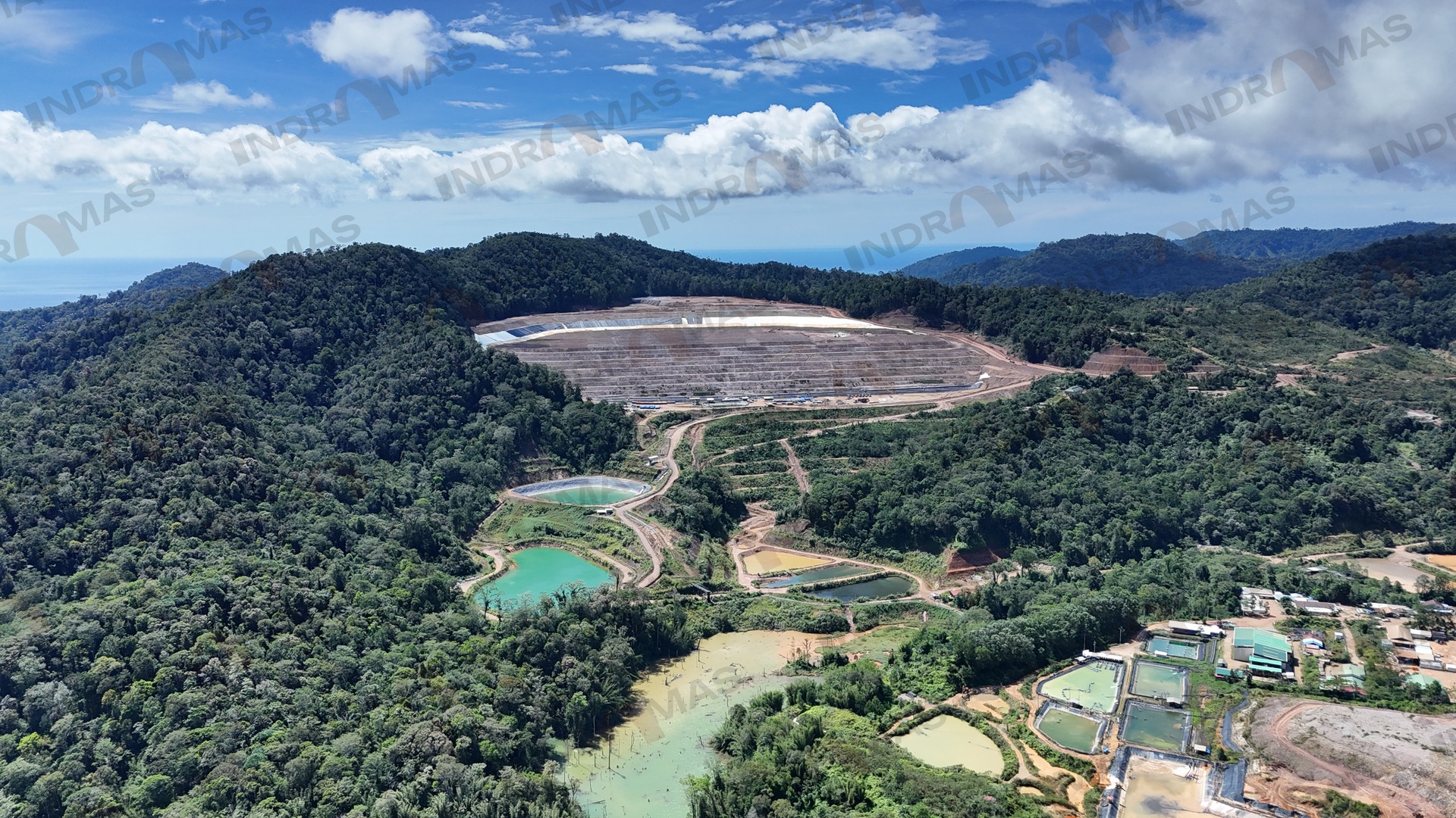 Aerial view of a lined heap leach pad and ponds in a forested mine site